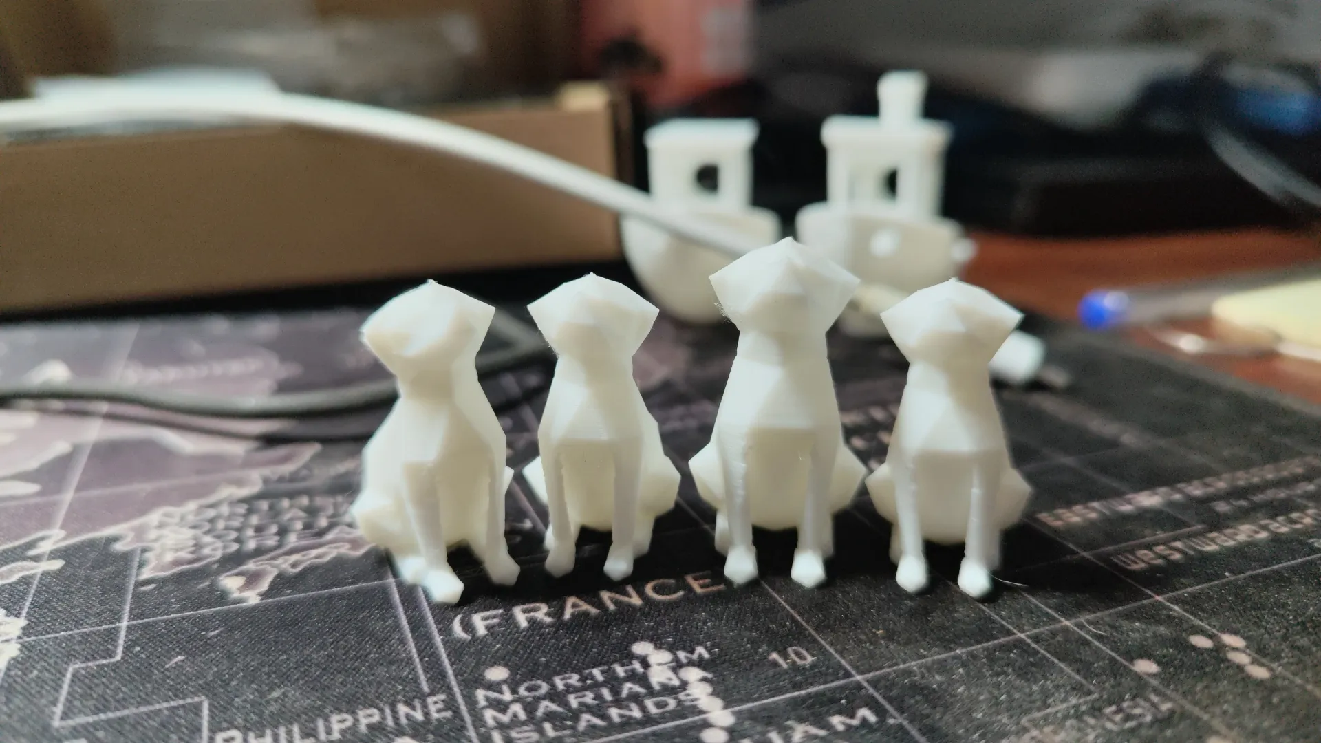 Manada de perros low-poly impresos en PLA blanco junto a un benchy