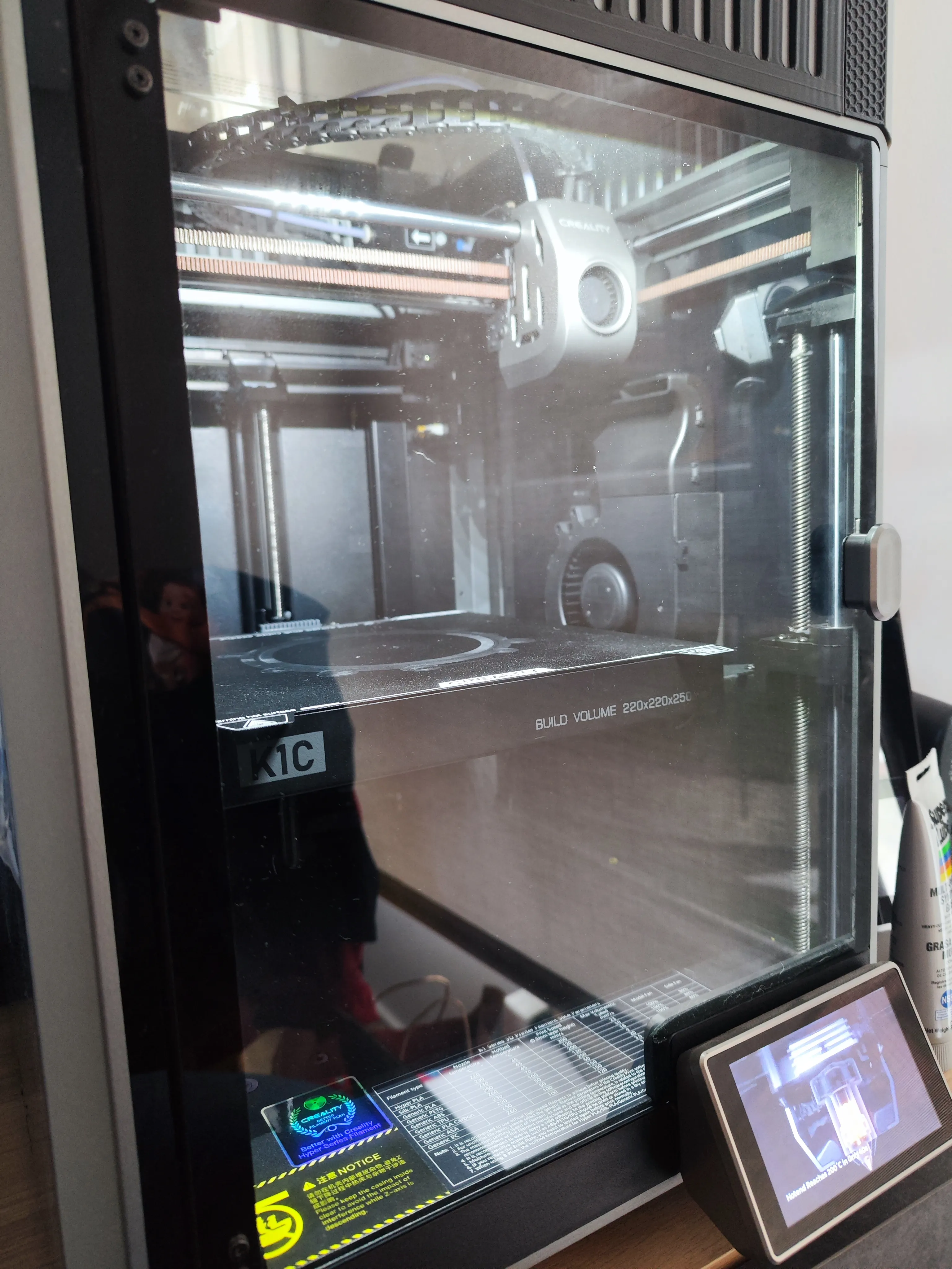 Creality K1C encendida mostrando su cámara cerrada y pantalla táctil